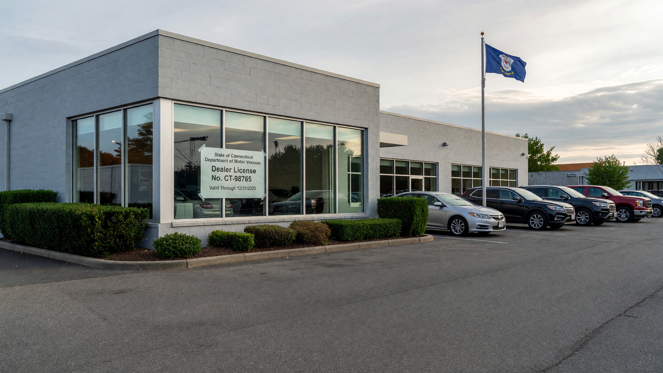 Exterior of a licensed Connecticut auto dealership with a state-issued dealer license posted in the office window.