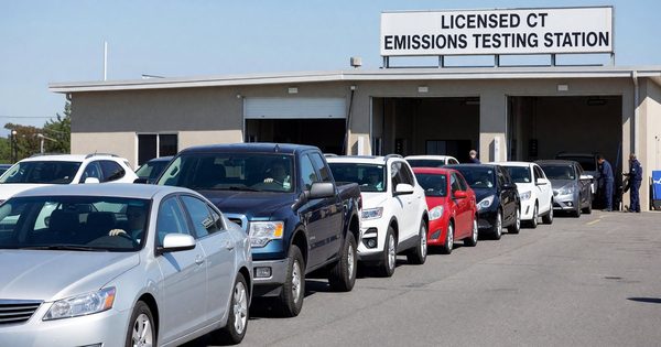 A mechanic running an OBD-II emissions test on a vehicle at a licensed testing station.